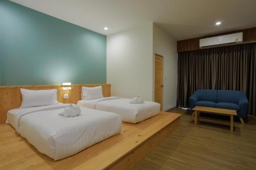 a hotel room with two beds and a blue chair at MOODs Boutique Hotel in Ban Phayom
