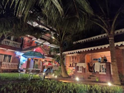 una casa con una palmera delante de ella por la noche en Blue Sea Beach Resort Malvan, en Malvan