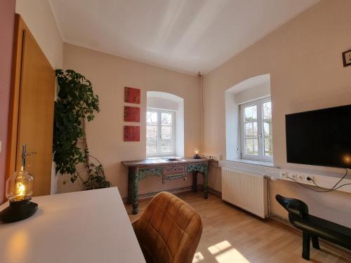 ein Wohnzimmer mit einem TV, einem Tisch und Stühlen in der Unterkunft Ferienwohnung am Trausdorfberg - Rosenblick in Goggitsch in Steiermark