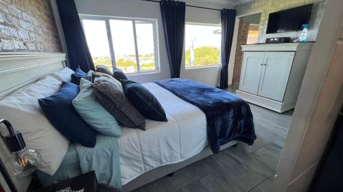 um quarto com uma cama com almofadas azuis e uma janela em Seaview Happy place em Bettyʼs Bay