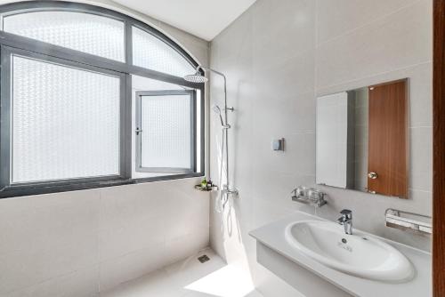 baño blanco con lavabo y ventana en 222 ROSÉ Hotel en Phu Quoc