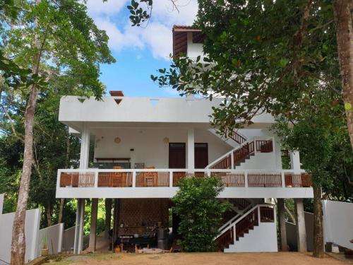a white building with stairs and trees in front of it at CoCoSuRf House, Luxury among palms in Hikkaduwa