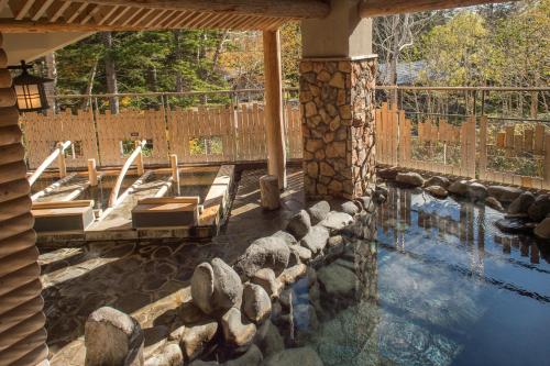 a swimming pool with chairs and a stone wall at La Vista Daisetsuzan in Higashikawa