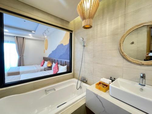 uma casa de banho com uma banheira, um lavatório e um espelho. em FLC Sea Tower - Căn Hộ Biển Quy Nhơn em Quy Nhon