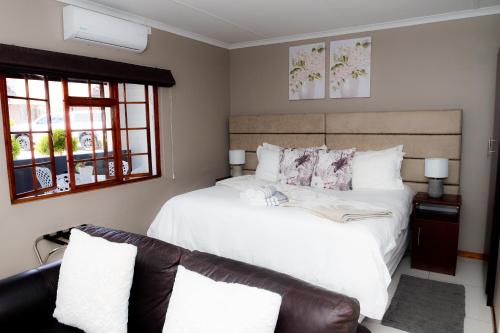 a bedroom with a white bed and a couch at Kleinplasie Guesthouse in Springbok