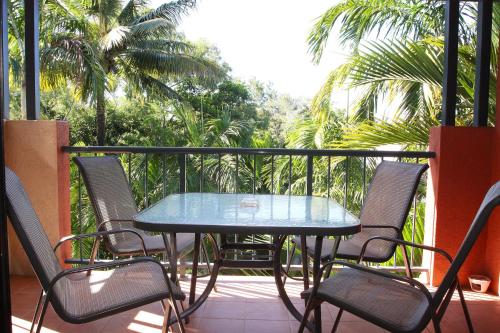 a table and chairs on a balcony with palm trees at Nautilus Holiday Apartments in Port Douglas