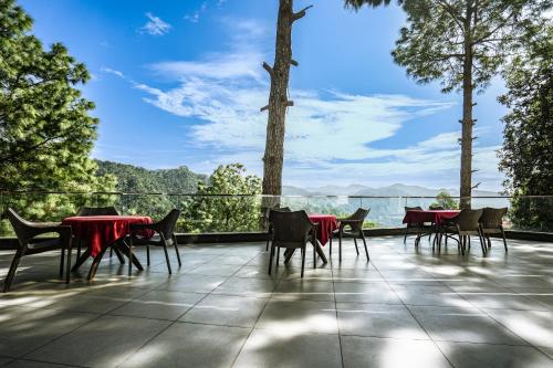 a patio with tables and chairs and a view of the mountains at The Golden Sunrise Hotel in Nainital