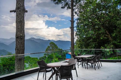 a balcony with tables and chairs and a view of mountains at The Golden Sunrise Hotel in Nainital