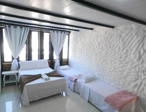 two beds in a room with windows at Nautillus Pousada in Arraial do Cabo