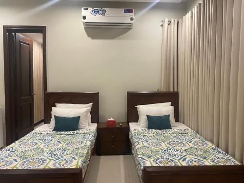 a bedroom with two beds and a air conditioner on the wall at Cozy Corner Homestay in Lahore