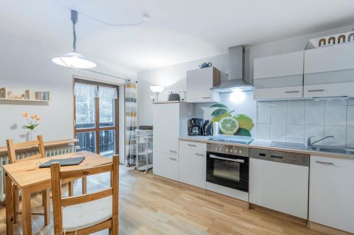 a kitchen with white cabinets and a wooden table at Apartment Entspannung - mitten im Ski- und Wandergebiet Spitzingsee in Schliersee