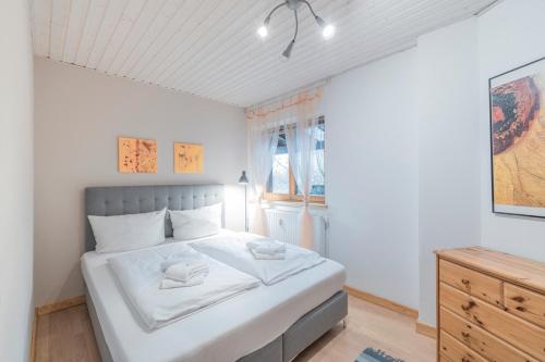 a white bedroom with a large bed and a dresser at Apartment Auszeit - mitten im Ski- und Wandergebiet Spitzingsee in Schliersee