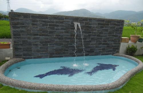 two dolphins swimming in a pool with a water fountain at Footprint Garden B&B in Dongshan