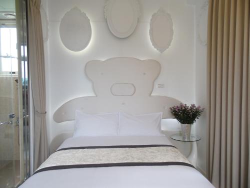 a white bedroom with a bed and a vase of flowers at Footprint Garden B&B in Dongshan