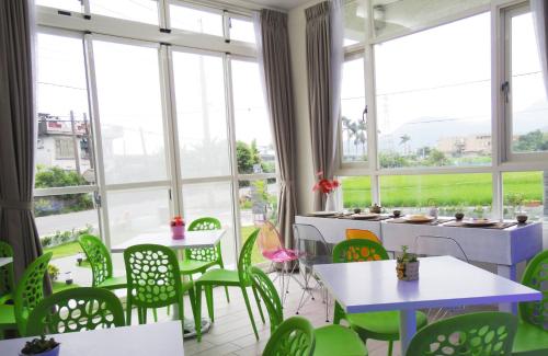 a room with green chairs and tables and windows at Footprint Garden B&B in Dongshan