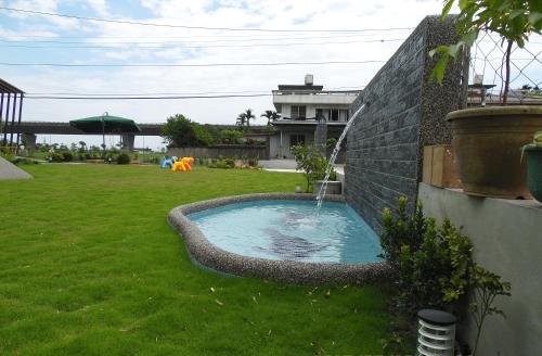 a swimming pool with a fountain in a yard at Footprint Garden B&B in Dongshan