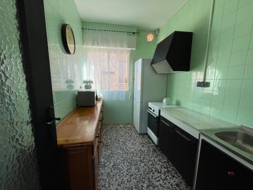 una pequeña cocina con fregadero y nevera. en Amplio apartamento junto al mar, en Calabardina