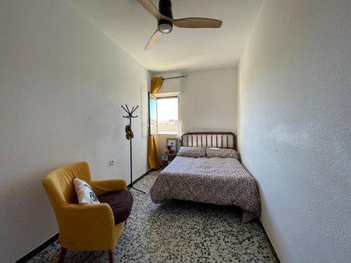 1 dormitorio con 1 cama, 1 silla y ventilador de techo en Amplio apartamento junto al mar, en Calabardina