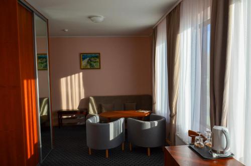 a hotel room with a table and chairs and a window at Viešbutis Ventainė in Ventė