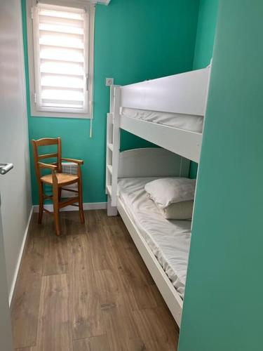 Cette chambre comprend 2 lits superposés et une chaise. dans l'établissement Bellevue - Appartement 60 m2 - 3 ch - vue mer - rénové à Wimereux Plage !, à Wimereux