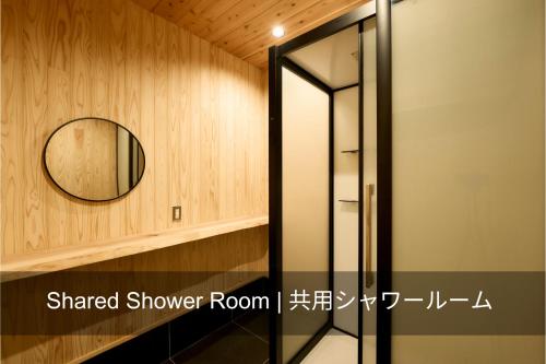 um espelho numa parede ao lado de uma cabina de duche em 自然人村 em Akiruno