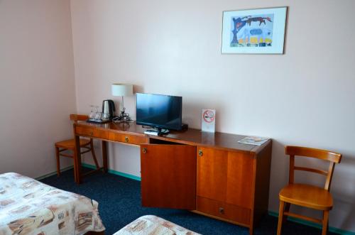 a room with a desk with a television and a bed at Viešbutis Ventainė in Ventė