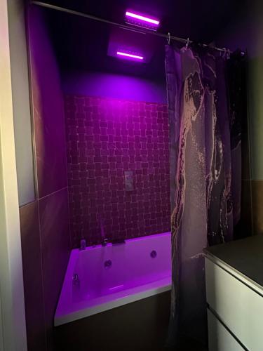 un bagno viola con vasca e luce viola di OliVia Rooms Sauna & Gym a Forlì
