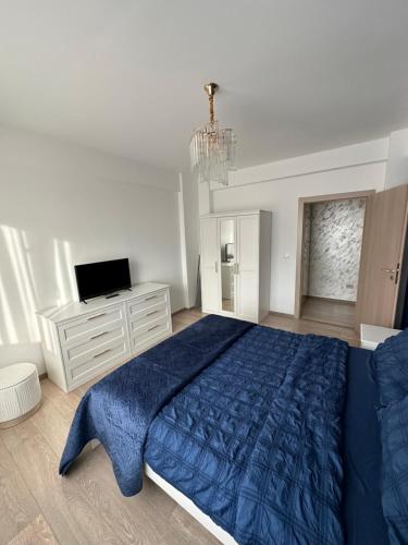 a bedroom with a blue bed and a television at Sunset view in Craiova