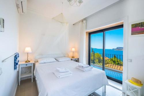 ein weißes Schlafzimmer mit einem Bett und einem großen Fenster in der Unterkunft Villa Jasmine Peninsula in Kaş