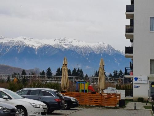 a snow covered mountain in the distance with cars and umbrellas at Apartament Ramonte in Zărneşti