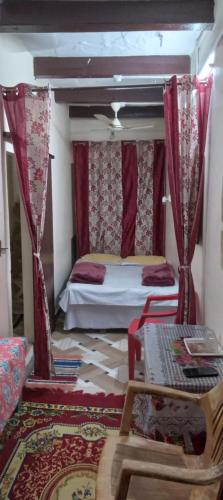バラナシにあるKALYANI HOME STAY IN VARANASIのベッドルーム1室(赤いカーテン付きの天蓋付きベッド1台付)