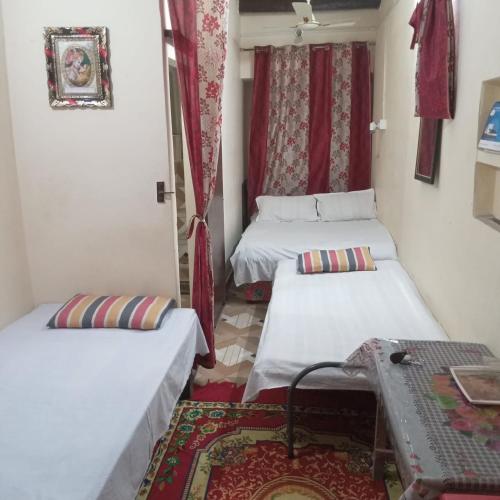 バラナシにあるKALYANI HOME STAY IN VARANASIの赤いカーテンが備わる小さな部屋のベッド2台
