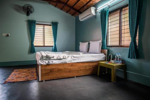 Un dormitorio con una cama con paredes azules y una mesa. en LEO COMFORTS RIVER SIDE en Hampi