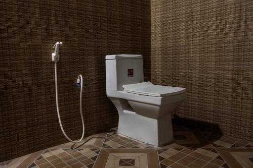 a bathroom with a toilet with a shower nozzle at LEO COMFORTS RIVER SIDE in Hampi