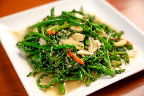 a plate of food with green vegetables on a table at Tamnanpar Resort in Ban Phe