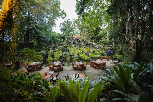 a group of tables in a garden with trees at Tamnanpar Resort in Ban Phe