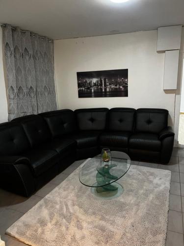ein Wohnzimmer mit einem schwarzen Sofa und einem Glastisch in der Unterkunft Le clos Petite Venise in Colmar