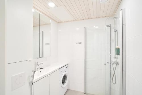 a white bathroom with a shower and a washing machine at Norden Homes Turku Nordic Apartment with Free Parking in Turku