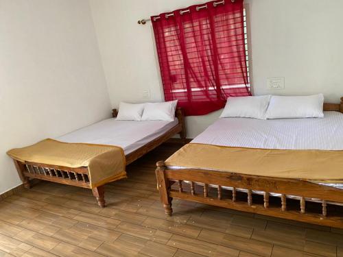 two beds in a room with a red window at Sugarcane Homestay in Attigundi