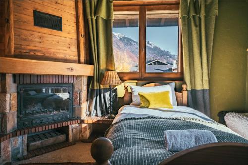 a bedroom with a fireplace and a bed in front of a window at The Fat Fox Lodge, Morzine in Montriond