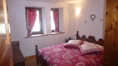 a bedroom with a red and white bed with two windows at Bilocale Entrèves CIR 116 in Courmayeur