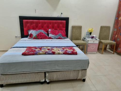 a bedroom with a large bed with a red headboard at Budget Hostel Rooms in Al Ain