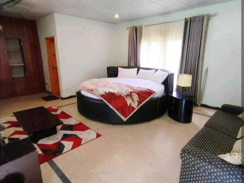 um quarto com uma cama grande e um sofá em C O Z Y Hut At Country Club Balakot em Bālākot