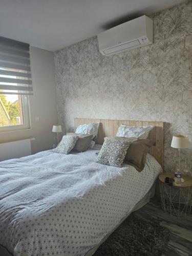 a bedroom with a large bed with a air conditioner on the wall at Chez Marianne in Wailly