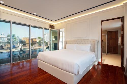 een slaapkamer met een wit bed en een groot raam bij Capitel Rama 4 in Bangkok