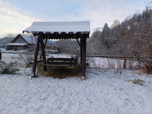 acovered bench with snow on it in a yard at Садиба у Курила з сауною та чаном на дровах in Shepot