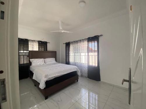 ein Schlafzimmer mit einem Bett in einem Zimmer mit Fenstern in der Unterkunft Sigma Theta Homes - Old Tafo in Kumasi