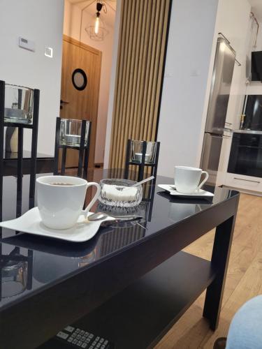 a black table with two cups and plates on it at Apartament Złota Dziewiątka in Wągrowiec