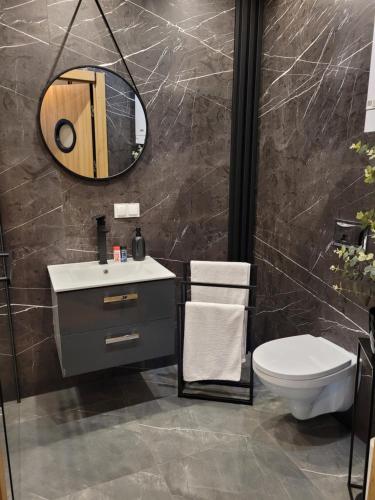 a bathroom with a sink and a toilet and a mirror at Apartament Złota Dziewiątka in Wągrowiec