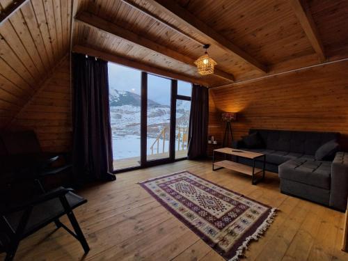 a living room with a couch and a large window at Kuro Kazbegi • ყურო ყაზბეგი in Stepantsminda